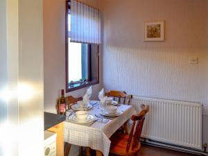 a dining room table with chairs and a table and a window at Butterhole Cottage in Kelton