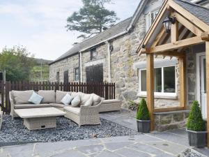 a patio with a couch and a stone house at Tyddyn Eli in Llangwm