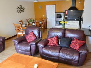 a living room with a leather couch and a table at Kestrel Cottage in Horning