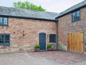 a brick building with a blue door and two windows at Woodhouse View in Helsby