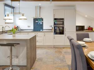 a kitchen with white cabinets and a wooden table at Woodhouse View in Helsby