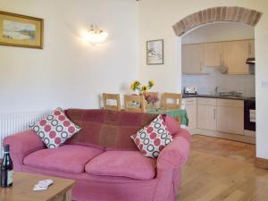 ein Wohnzimmer mit einem rosa Sofa und einer Küche in der Unterkunft Cothi Cottage in Llanfynydd