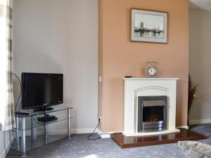 a living room with a fireplace and a tv at Sea Breeze Cottage in Buckie