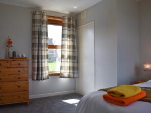 a bedroom with a bed and a dresser and a window at Sea Breeze Cottage in Buckie