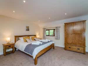 a bedroom with a large bed and a wooden cabinet at Rhiew Banc in Aberhafesp