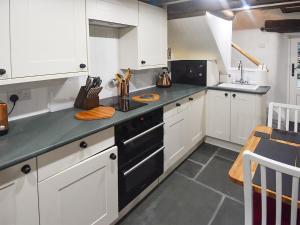 a kitchen with white cabinets and a black stove top oven at Field House Cottage - Uk12573 in Borrowdale