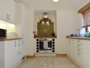 uma cozinha com armários brancos e um fogão em Lambing Shed - Uk12380 em Lydney