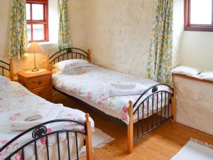 a bedroom with two beds and a table with a lamp at Cowslip - Uk12060 in Lower Boscaswell