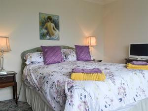 um quarto com uma cama grande e almofadas roxas em Swn-y-wylan em Criccieth
