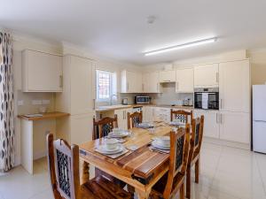 a kitchen with a wooden table and chairs and a kitchen with white cabinets at Dawson Park 4 - Uk12663 in Mablethorpe