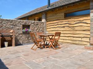 una mesa de madera y sillas en un patio de piedra en Lambing Shed - Uk12380, en Lydney