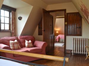 a living room with a red couch and a bedroom at Bakers Cottage in Hotham