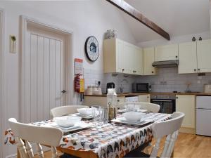a kitchen with a table with chairs and a table cloth at Willow in Harrietsham
