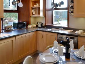 East Lodge في Kingholm Quay: مطبخ بدولاب خشبي ومغسلة وطاولة