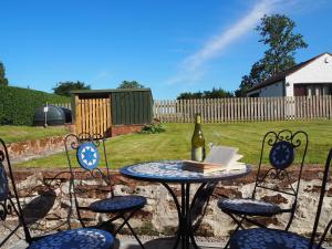 a table and chairs with a bottle of wine and a book at East Lodge in Kingholm Quay