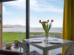 a white table with a vase of flowers on a window at The Isle View Nest - Uk13547 in Broadford