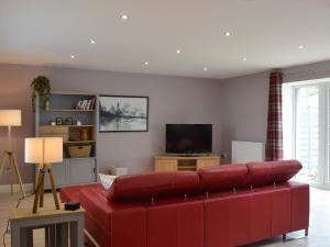 a red couch in a living room with a television at Torcross Barn in Tarbolton