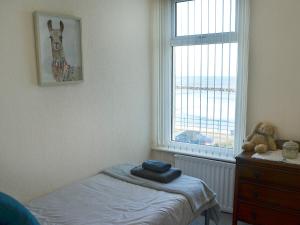 a bedroom with a bed and a window and a teddy bear at Violet Cottage in Woodhorn