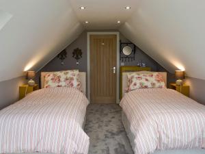 a attic room with two beds and a staircase at Torcross Barn in Tarbolton