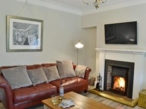 uma sala de estar com um sofá de couro castanho e uma lareira em Altbeg em Brodick