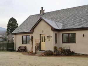 a white house with a black roof at Rowan Cottage in Aviemore