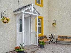 a white entry door to a building with a table and benches at Bumblebee Nook in Penrith
