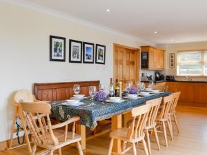 a dining room with a table with chairs and a kitchen at Saffron in Portpatrick