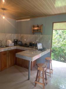 a kitchen with a counter with a laptop and two stools at La Reina del Mar in Drake