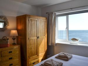 a bedroom with a wooden cabinet and a window at Craster View in Craster