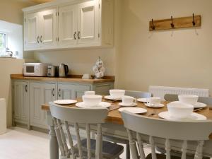 a kitchen with a wooden table and white chairs at Ivy Cottage in Grassington