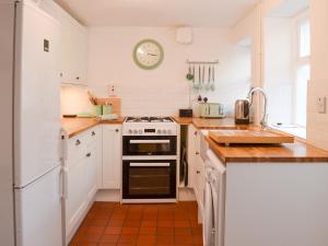 a kitchen with white cabinets and a stove top oven at Honeysuckle Cottage in Watchet