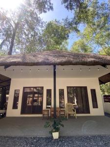 San Felipe的住宿－The Beach House Liwa，一间设有稻草屋顶和桌椅的小房子