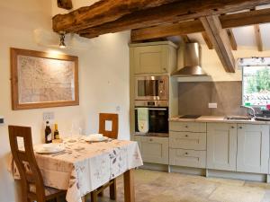 a kitchen with a table with chairs and a stove at Gelderslack Barn in Nateby