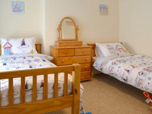 a bedroom with two beds and a dresser and a mirror at Seagulls Rest in Filey