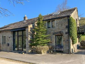 a stone house with a tree in front of it at Hilltop Barn in Starbotton