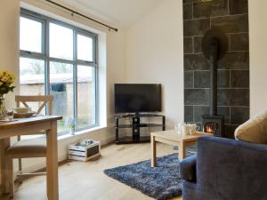 a living room with a fireplace and a tv at Fig Tree Cottage in Pancrasweek