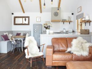 a living room with a couch and a kitchen at The Barn in Brighstone