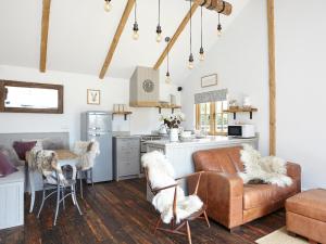 a living room with a couch and a kitchen at The Barn in Brighstone