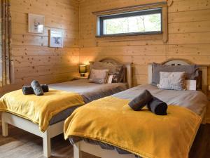 two beds in a log cabin with a window at Birch Lodge - Uk30006 in Lindal in Furness