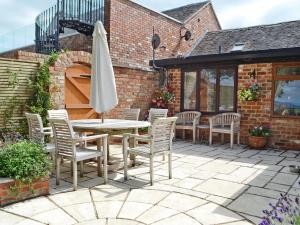 a patio with a table and chairs and an umbrella at The Cottage in Cheltenham