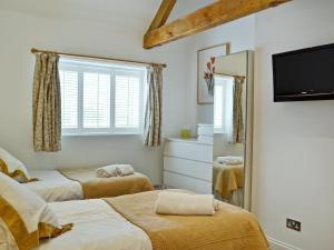 um quarto com 2 camas, uma televisão e um espelho. em The Cottage em Cheltenham
