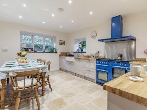 a kitchen with blue appliances and a table with chairs at Pwll Farmhouse in Llanllawdog