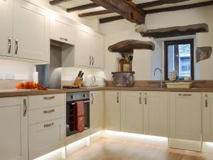 a kitchen with white cabinets and a sink at Penfold in Dockray