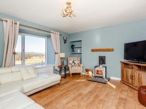 a living room with a white couch and a fireplace at Knocknahighle in Cromdale