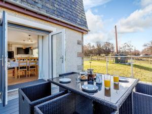 een patio met een tafel en stoelen op een balkon bij Knocknahighle in Cromdale