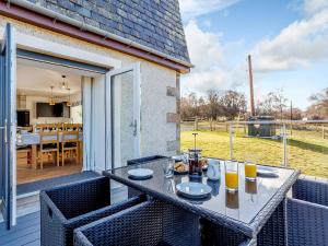 a patio with a table and chairs on a balcony at Knocknahighle in Cromdale