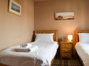 a bedroom with two beds with white sheets and a night stand at Perran Cottage in Reighton