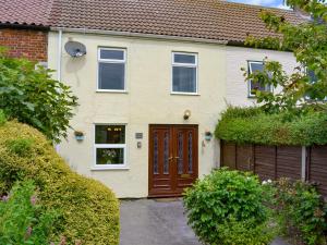 una casa con una puerta marrón y una valla en Cushty Cottage, en Winterton-on-Sea