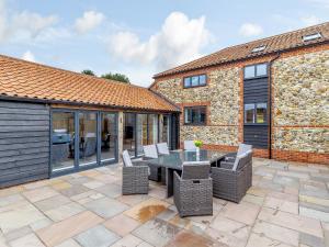 a patio with a table and chairs and a building at Skylark Barn-uk31354 in Swaffham