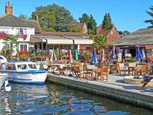 a restaurant with tables and chairs and a boat in the water at Tracara Cottage in Horning
